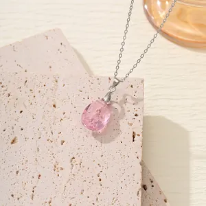 Detailansicht eines rosa Tropfen-Kristallanhängers an einer zarten silbernen Halskette.