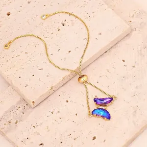 Nahaufnahme eines eleganten Goldarmbands mit Schmetterling und violettblauen Kristallen