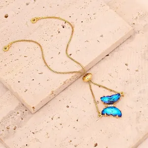 Detailansicht des blauen Zirkonia-Schmetterlingsanhängers an einem goldenen Armband.