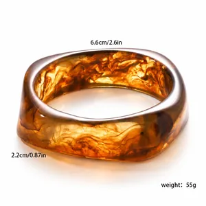 Detailed view of an irregular marbled resin bangle with amber swirls and polished finish