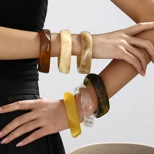 Close-up of irregular marbled resin bangles in various colors on a model's wrist
