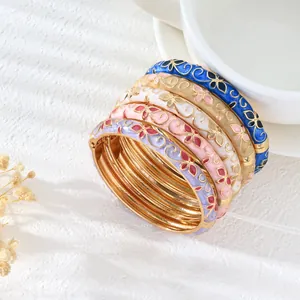 Detalle de brazaletes apilables vintage con motivos florales de trébol en esmalte de colores