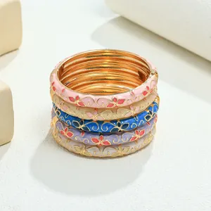 Detalle de brazaletes de esmalte de colores apilados con diseño floral vintage y acabado dorado