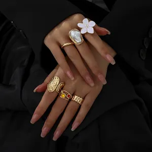 Detailansicht goldener Lavatextur-Ringe mit Barockperle und weißer Blütenverzierung