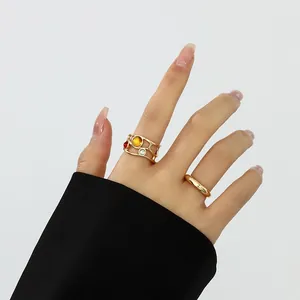 Nahaufnahme eines goldfarbenen Rings im Liquid-Lava-Stil mit bunten Edelsteinen an der Hand