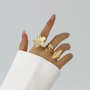 Nahaufnahme von goldenen Lavaringen mit Blumen- und Wellendesign an einer Hand
