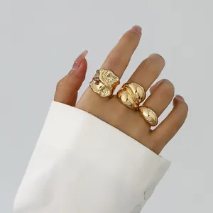 Detailansicht von drei unregelmäßigen goldenen Ringen im Liquid-Lava-Stil an der Hand