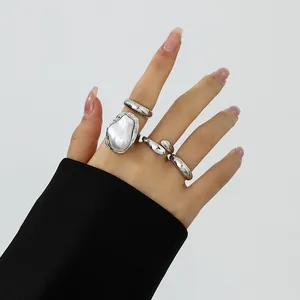 Detailaufnahme von silbernen Flüssiglavaringen und Barockperlenring an der Hand