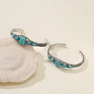 Close-up of bohemian vintage turquoise open cuff bracelets with intricate silver carvings.