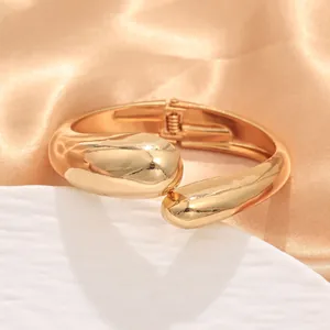 Dettaglio di bracciale rigido dorato ondulato irregolare con finitura lucida