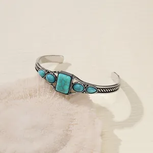 Vintage Bohemian turquoise open cuff bracelet resting on a white textured coral prop