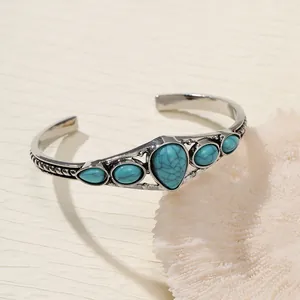 Detailed view of a vintage bohemian cuff bracelet with teardrop turquoise stones.