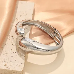 Vista dettagliata di un bracciale argento minimalista con finitura lucida irregolare.