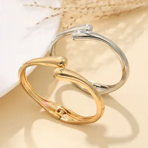 Vista ravvicinata di bracciali rigidi a onda in oro e argento con finitura lucida
