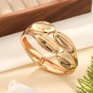 Primo piano di un bracciale rigido dorato con trama ondulata e finitura lucida