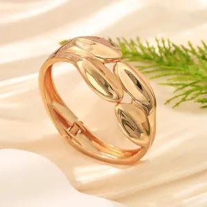 Vista dettagliata di un bracciale rigido dorato lucido con design a onde irregolari
