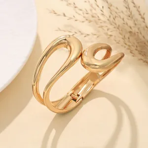 Vista dettagliata di un bracciale dorato irregolare con finitura in metallo lucido