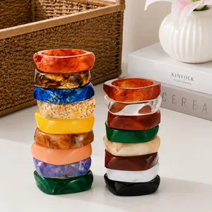Close-up detail of stacked colorful irregular marbled resin bangles with a polished finish.
