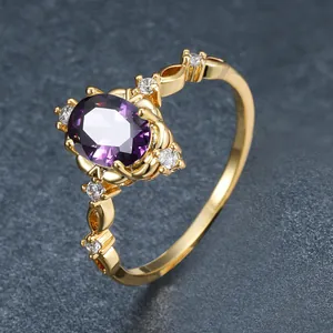 Gros plan d'une bague dorée vintage avec une pierre violette et zircons latéraux