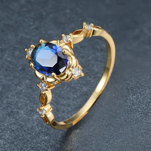 Vue détaillée d'une bague dorée élégante avec zircon saphir bleu et pierres claires.