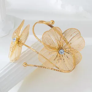 Detailopname van een gouden opengewerkte bloemenarmband met kristallen accenten