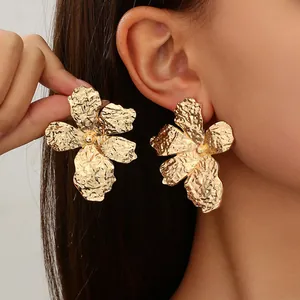 Detail showing oversized gold textured flower earrings with vintage hammered metal style