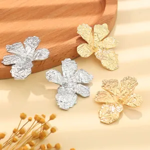 Detailed macro view showing the unique textured gold and silver vintage metal flower earrings