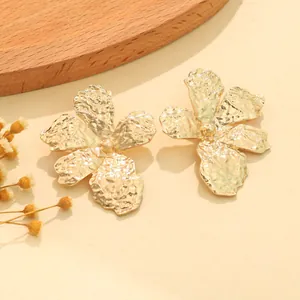 Close-up of vintage gold hammered metal flower stud earrings with elegant texture