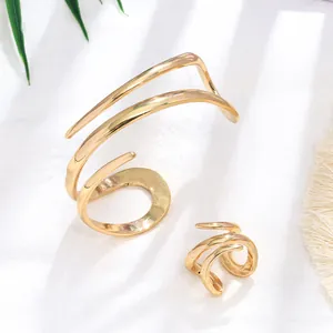 Set di gioielli a spirale dorati con bracciale rigido aperto e anello multistrato coordinato