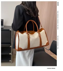 Moderne Canvas-Reisetasche mit Lederbesatz am Modell in stilvoller Innenraumumgebung