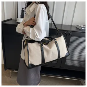 Beige Segeltuch-Reisetasche mit schwarzem Besatz, von einer Frau im Lifestyle-Setting getragen