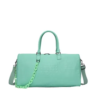 High-quality frontal view of a mint green crocodile-texture duffel bag with a decorative chain