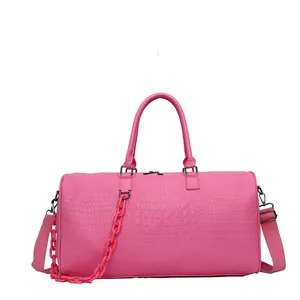 Detailed view of pink crocodile embossed travel bag with top handle and plastic chain strap