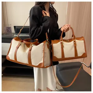 Zwei Reisetaschen aus Canvas und braunem Leder, gehalten von einem Modell im Lifestyle-Stil.