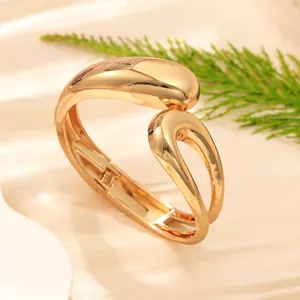 Primo piano dettagliato di un bracciale a onda dorato minimalista con finitura lucida