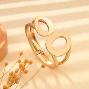 Dettaglio di un bracciale rigido minimalista dorato con doppio accento ovale