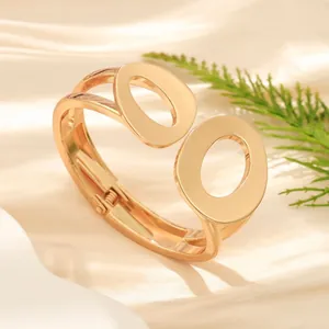 Vista dettagliata di un bracciale rigido dorato minimalista con design a doppio ovale lucido