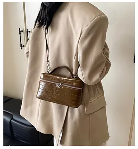 Detailed side view of a brown crocodile-patterned box handbag worn with a beige blazer.