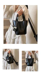 Nahaufnahme einer schwarzen minimalistischen Eimertasche aus Leder, gehalten von Model