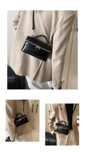 Close-up detail of the stylish black crocodile textured mini box bag on a beige blazer