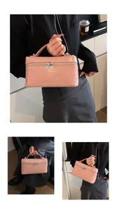 Details of pink crocodile pattern box handbag held by a model in a stylish setting.