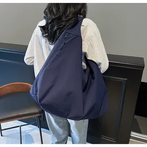 Vista posterior de un gran bolso bandolera de lona azul marino llevado por una modelo