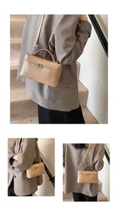 Detail view of a beige croc-embossed box bag styled with a grey blazer on stairs