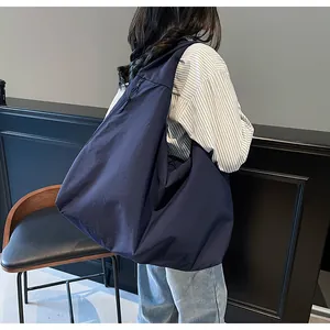 Bolso bandolera azul marino grande mostrado en una modelo en un interior moderno