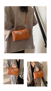 Close-up of a stylish brown crocodile embossed box bag carried by a model in a grey blazer.