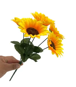 Hand hält einen Strauß hellgelber künstlicher Sonnenblumen mit realistischen Details