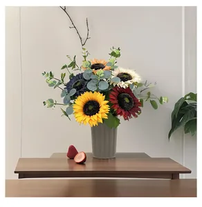 Künstliche bunte Sonnenblumen und Eukalyptus in einer grauen Vase für die Heimdeko