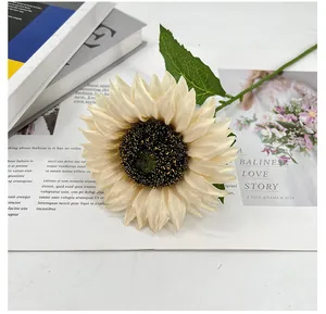 Detailaufnahme einer elfenbeinfarbenen künstlichen Sonnenblume auf Magazinhintergrund