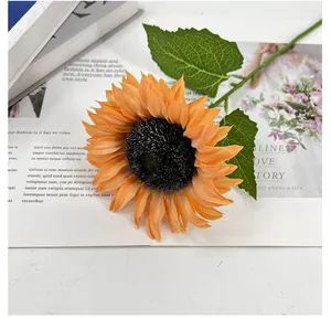 Detailaufnahme einer künstlichen Sonnenblume mit orangefarbenen Blütenblättern und Stiel
