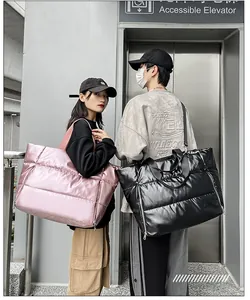 Dos modelos que llevan bolsos de mano acolchados de gran tamaño en colores rosa y negro.